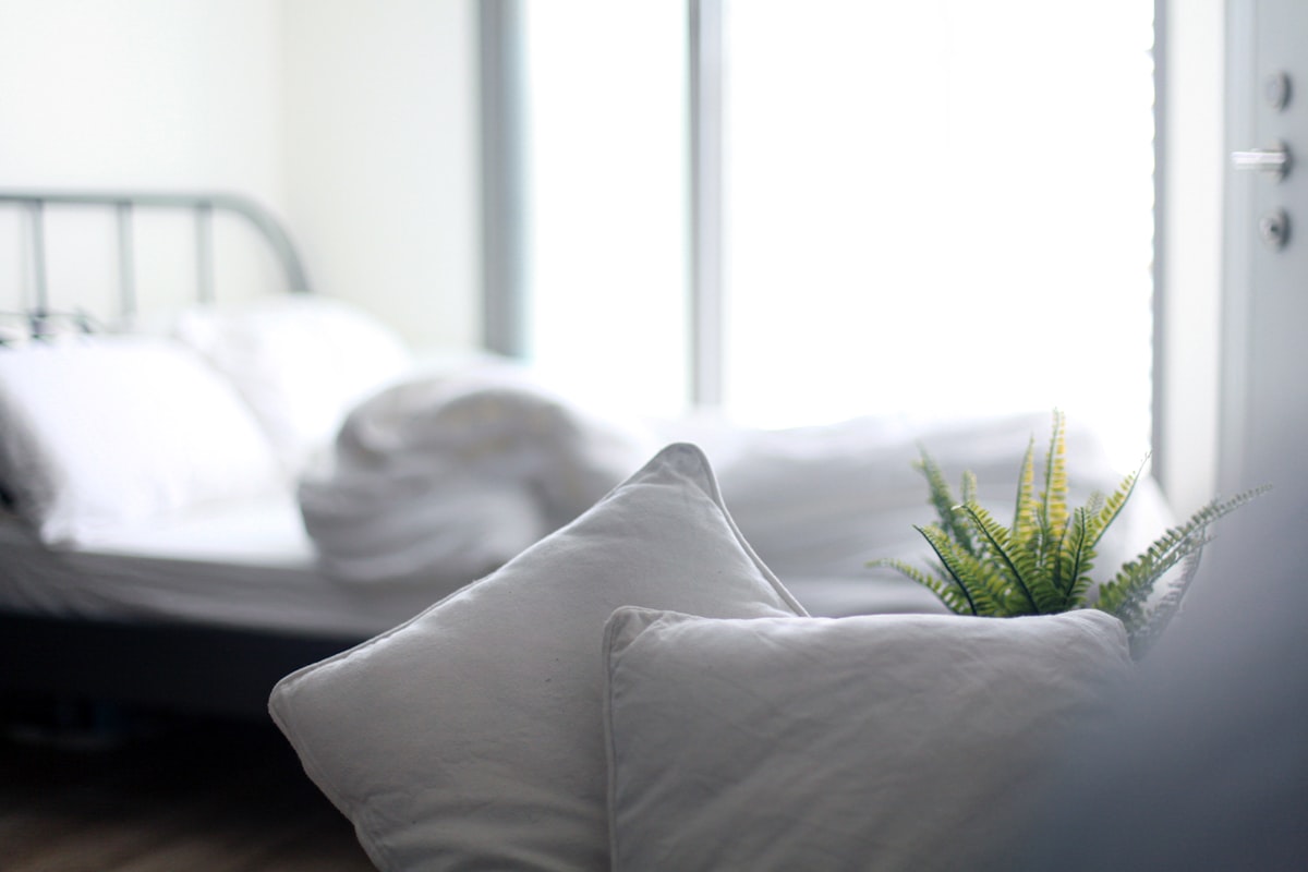 Close-up of a white bed pillow resting against crisp white sheets