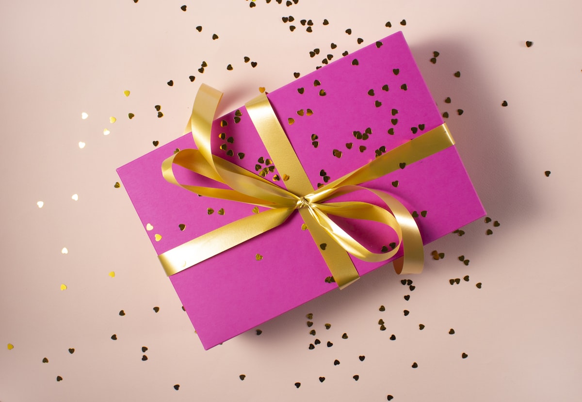 A pink wrapped gift box tied with a yellow ribbon