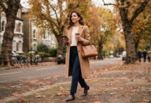Old money style outfit: camel coat, cable-knit sweater, navy trousers and loafers